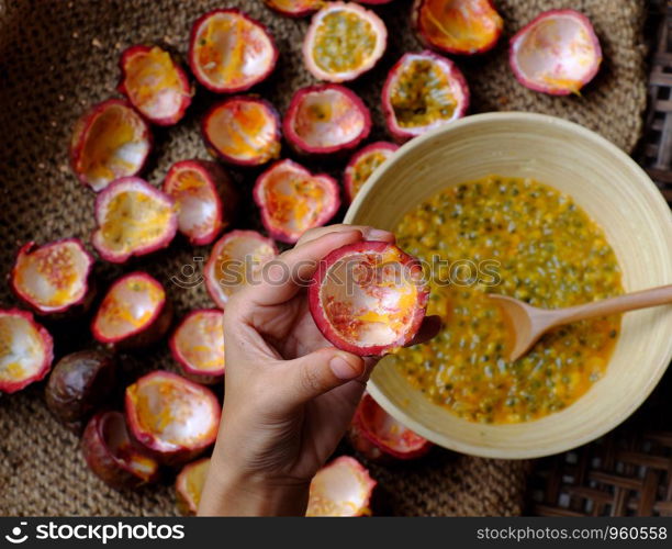 Top view woman hand processing passion fruit by cut in half Passiflora edulis, with a spoon people take soft pulp and seeds inside a hard rind to bowl