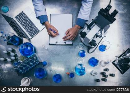 top view workspace in laboratory with microscope, laptop, and laboratory tools