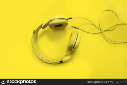 Top view yellow headphones and Convention Aux cable 3.5 mm with copy space. Isolated on yellow background