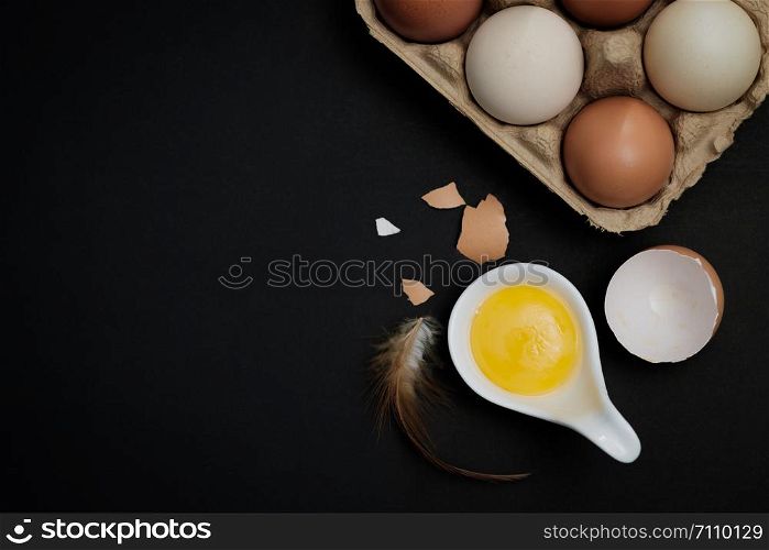 Top view-Yolk and Eggs in white ceramic spoon arranged on the black background, Egg is beneficial to the body, Food concept, with copy space.