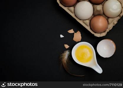 Top view-Yolk and Eggs in white ceramic spoon arranged on the black background, Egg is beneficial to the body, Food concept, with copy space.