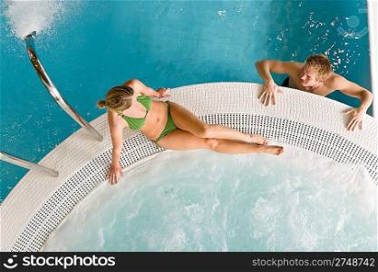 Top view - young couple relax in swimming pool sitting at bubble bath