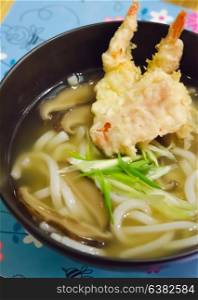 top views udon noodles with shrimp tempura in black bowl , Japanese food