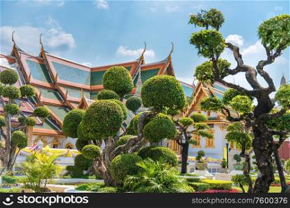Topiary garden with trimmed trees on green lawn in front of Grand Palace in Bangkok, Thailand