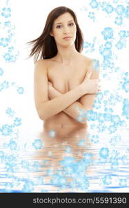 topless brunette standing in water with flowers