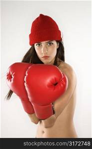 Topless caucasian woman wearing boxing gloves and hat.