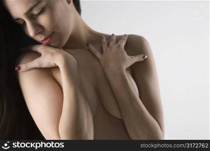 Topless Caucasian woman with arms crossed looking to the side.