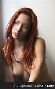 Topless portrait of pretty redhead young woman against white background.