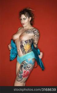 Topless tattooed woman pulling off corset.