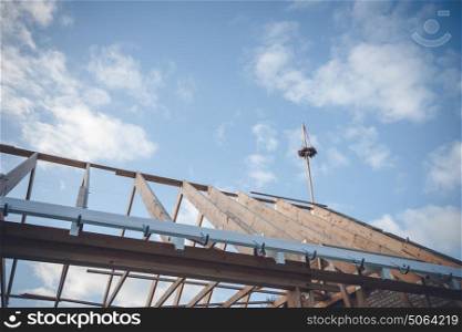 Topping-out ceremony with a wreath on the top of the roof construction on a blue sky