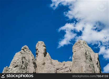 Tops of gray sandstone cliffs against cloud and blue sky
