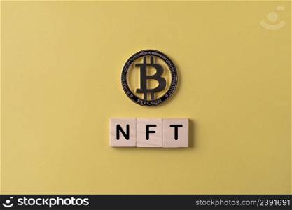 Topview photo on NFT word with Bitcoin blockchain cryptocurrency coin on yellow background