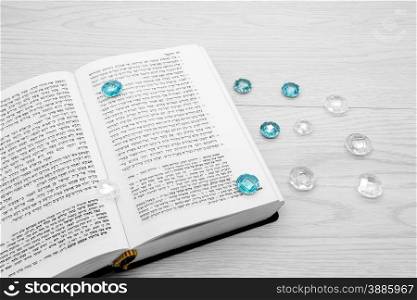 Torah book with precious stones on a light wooden background.