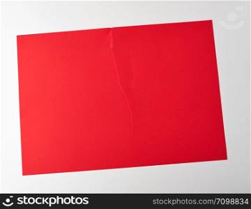 torn in half empty red sheet of paper on white background, close up
