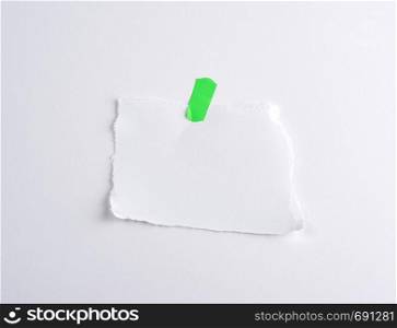 torn off white piece of paper glued to green velcro, white background