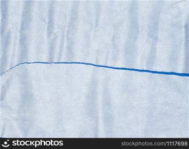 torn piece of white parchment paper on a blue background, close up