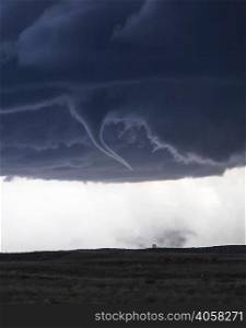 Tornado with funnel cloud over field landscape