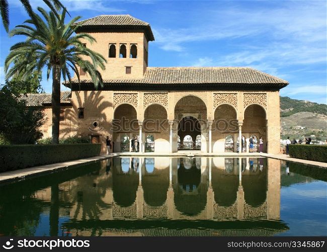 Torre de las Damas and its reflection in a pool in the Alhambra of Granada, Spain.