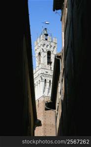 Torre del Mangia belltower seen through darkened alleyway.