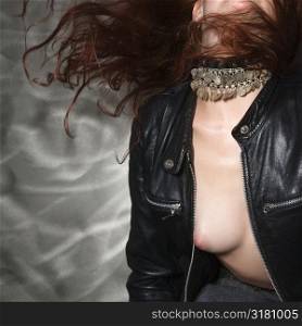 Torso of partially nude Caucasian woman in leather jacket with long hair blowing.