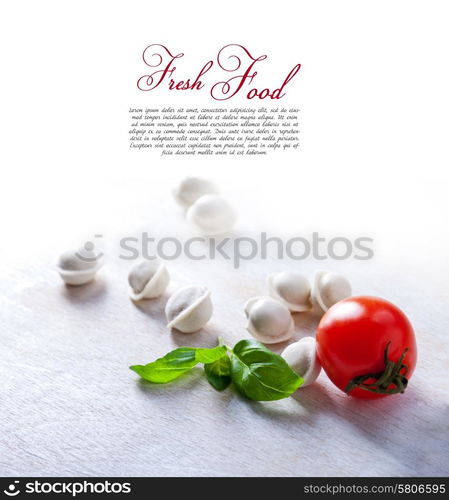 Tortellini and vegetables on white wooden background