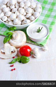 Tortellini and vegetables on white wooden background