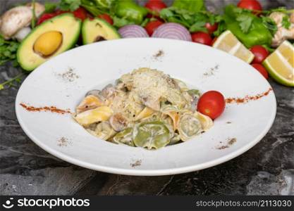Tortellini with vegetables on white plate on marble table
