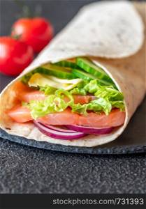 Tortilla wrap with salmon, cheese and vegetables on the stone board