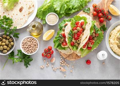 Tortilla wraps with chickpea hummus, fresh tomatoes and olives, vegan food