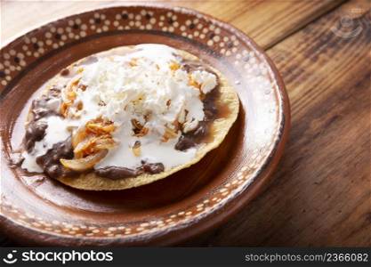 Tostadas de Tinga de Pollo. Traditional mexican homemade chicken toasts with beans, chicken breast meat, onion and chipotle chili topped with sour cream and fresh white cheese