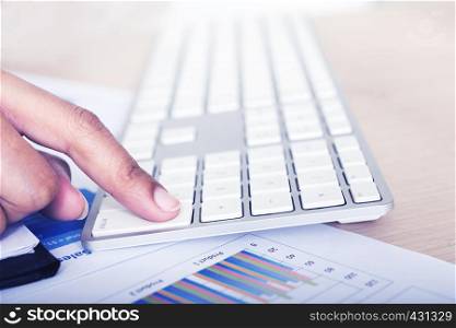 Touching keyboard in business workplace with paper graphs and diagrams.Business finance analysis concept.