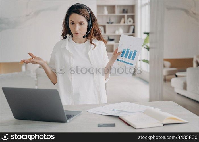 Tough woman has corporate internet session on laptop. Pretty european girl demonstrates charts and works on startup project. Businesswoman is brainstorming online. Remote business on quarantine.. Tough woman has internet session on laptop. Girl demonstrates charts and works on startup project.