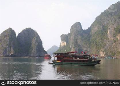 Tourboats in a bay rock formations in the background, Halong Bay, Vietnam