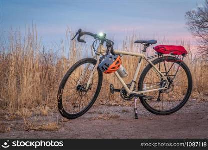 touring bicycle at dusk with headlight on in late fall or winter scenery in northern Colorado - a gravel trail in Riverbend Ponds Natural Area in Fort Collins