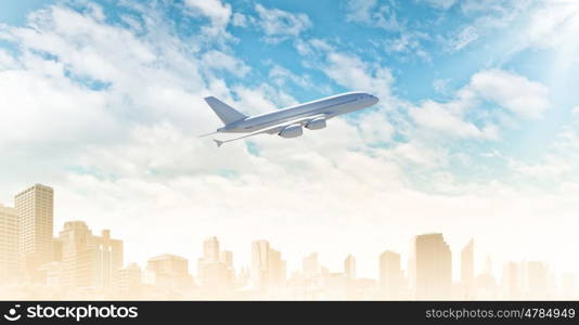 Tourism and transport. Airplane flying in blue sky above modern city