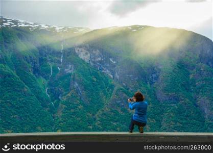 Tourism and travel. Woman tourist taking photo with camera, enjoying mountains fjords view in Sogn og Fjordane county. Norway Scandinavia.. Female tourist taking photo at norwegian fjord