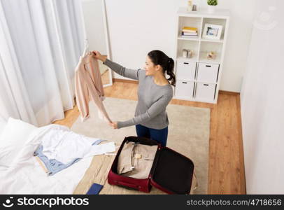 tourism, business trip, people and luggage concept - happy young woman packing travel bag at home or hotel room. woman packing travel bag at home or hotel room. woman packing travel bag at home or hotel room