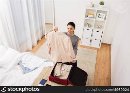 tourism, business trip, people and luggage concept - happy young woman packing travel bag at home or hotel room. woman packing travel bag at home or hotel room