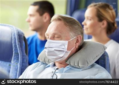 tourism, healthcare and pandemic concept - senior man wearing face protective medical mask for protection from virus disease sleeping in travel bus with neck pillow. senior man in mask sleeping in travel bus