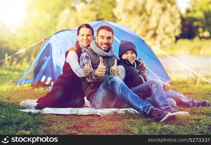 tourism, hike and travel concept - happy family over tent at camp site showing thumbs up gesture. happy family with tent at camp site