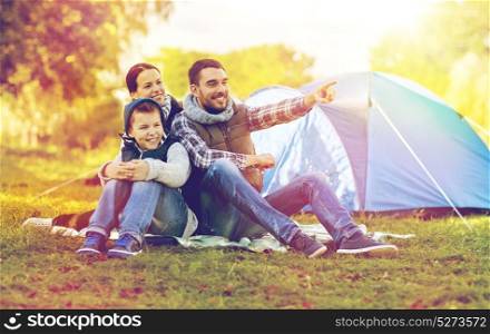 tourism, hike and travel concept - happy family over tent at camp site pointing finger to something. happy family with tent at camp site