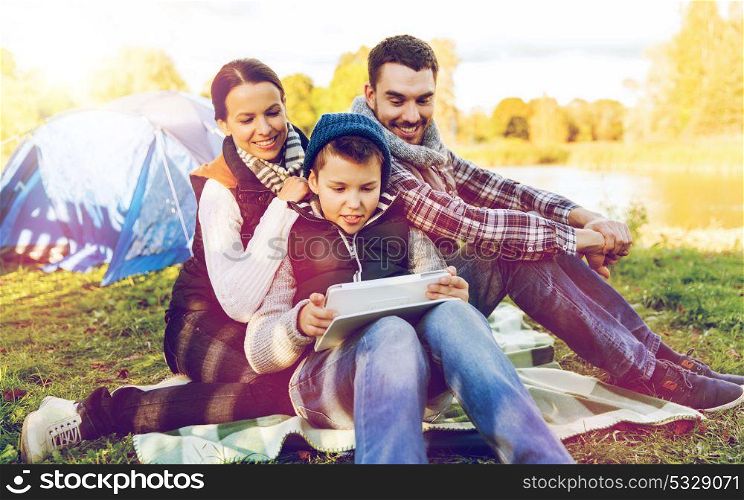 tourism, hike, technology and travel concept - happy family with tablet pc computer and tent at camp site. happy family with tablet pc and tent at camp site