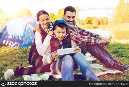 tourism, hike, technology and travel concept - happy family with tablet pc computer and tent at camp site. happy family with tablet pc and tent at camp site