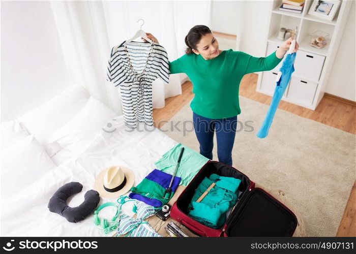 tourism, people and luggage concept - happy young woman packing travel bag at home or hotel room. woman packing travel bag at home or hotel room