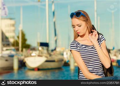 Tourism relax and people concept. Fashion blonde girl with blue heart shaped sunglasses in marina against yachts in port
