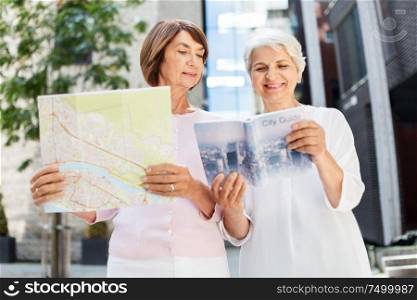 tourism, travel and friendship concept - happy senior women with city guide and map on tallinn street. senior women with city guide and map on street