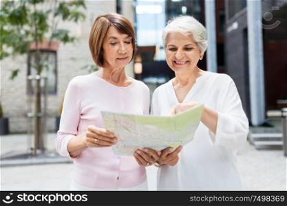 tourism, travel and friendship concept - happy senior women with city map on street in tallinn. senior women with city map on street in tallinn