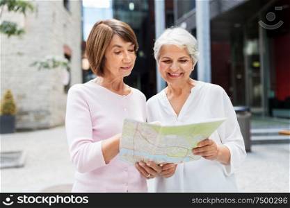 tourism, travel and friendship concept - happy senior women with city map on street in tallinn. senior women with city map on street in tallinn