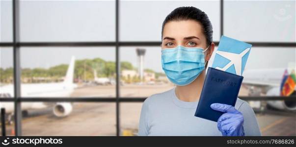 tourism, travel and health care concept - young woman wearing face protective medical mask for protection from virus disease with air ticket and passport over airport background. woman in mask with passport and ticket at airport