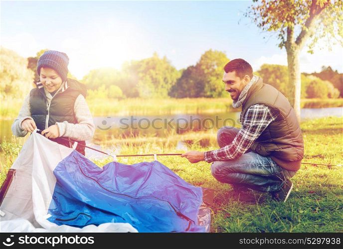 tourism, travel and hike concept - happy father and son hiking and setting up tent outdoors. happy father and son setting up tent outdoors